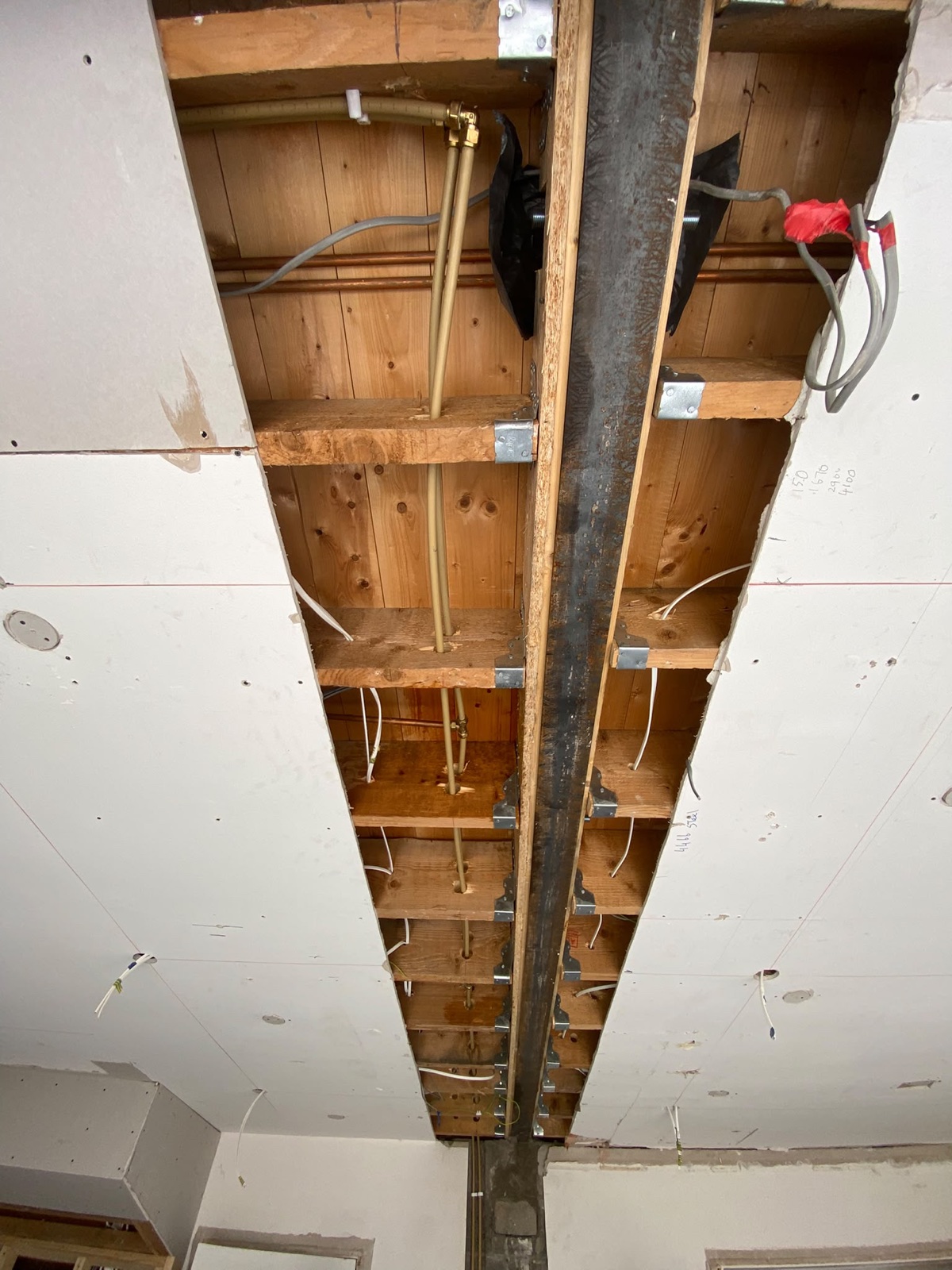 Close-up of a steel beam installed into an exposed ceiling structure.