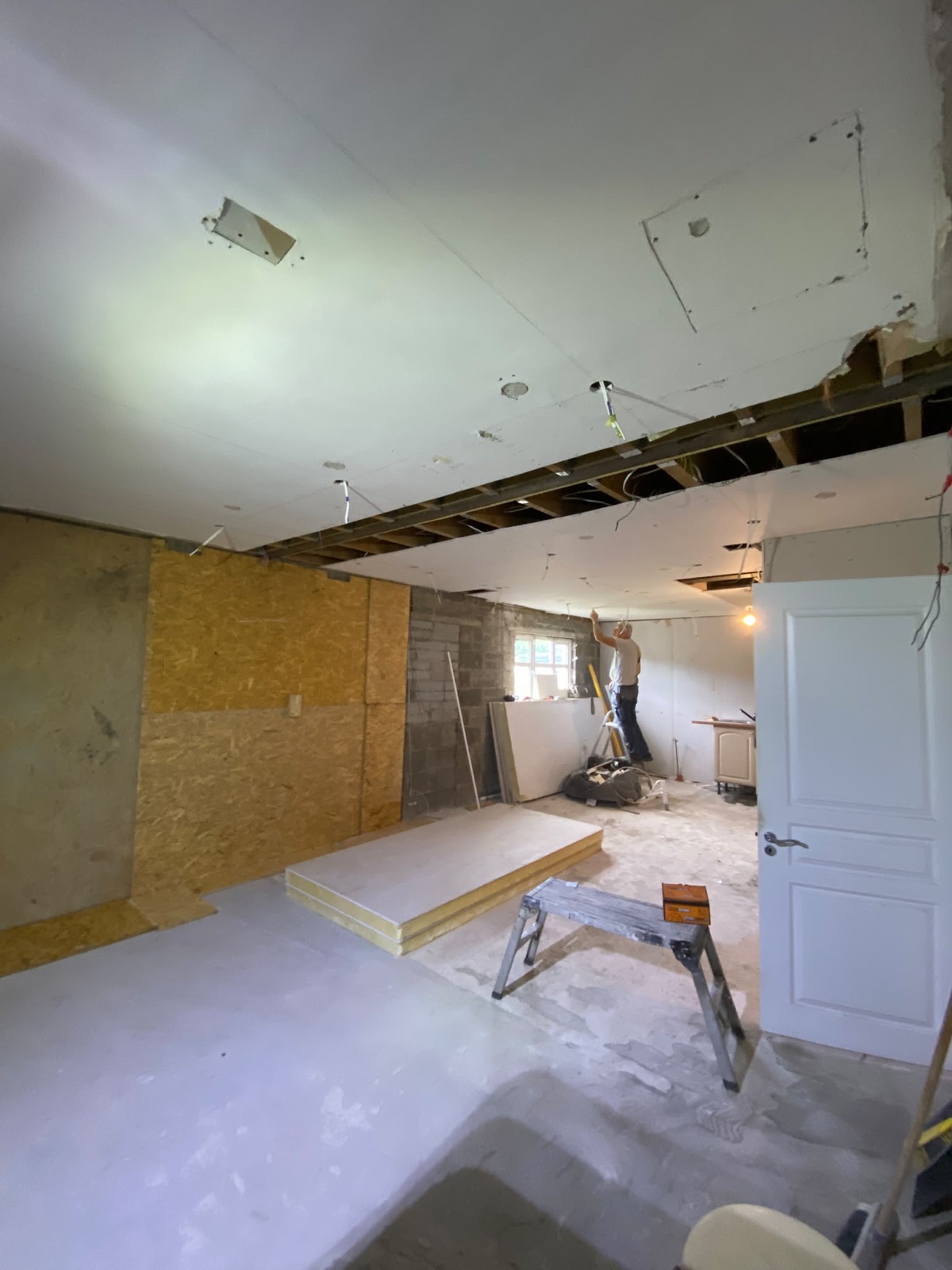 Open-plan room renovation with ceiling opened for a flush structural beam.