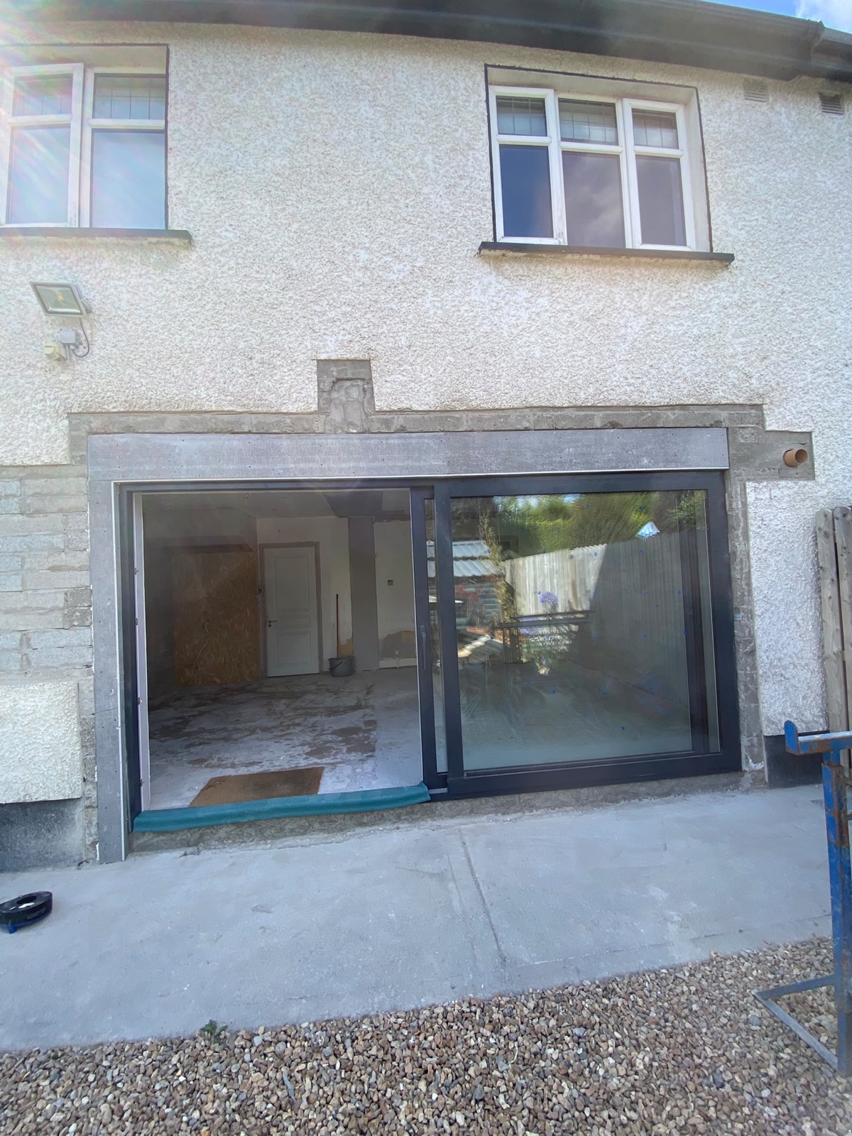 Large sliding patio door fitted into a new rear opening with steel support visible above.