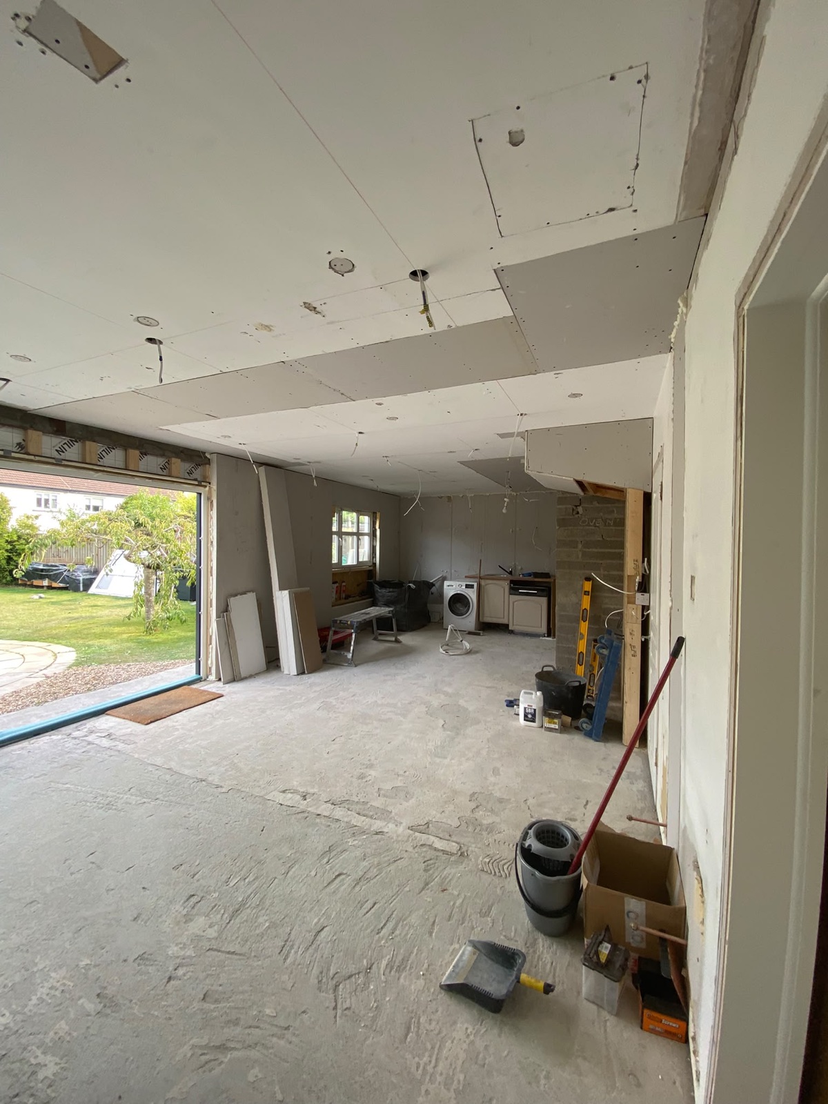 Ceiling plasterboarded after flush beam installation in an open-plan room.