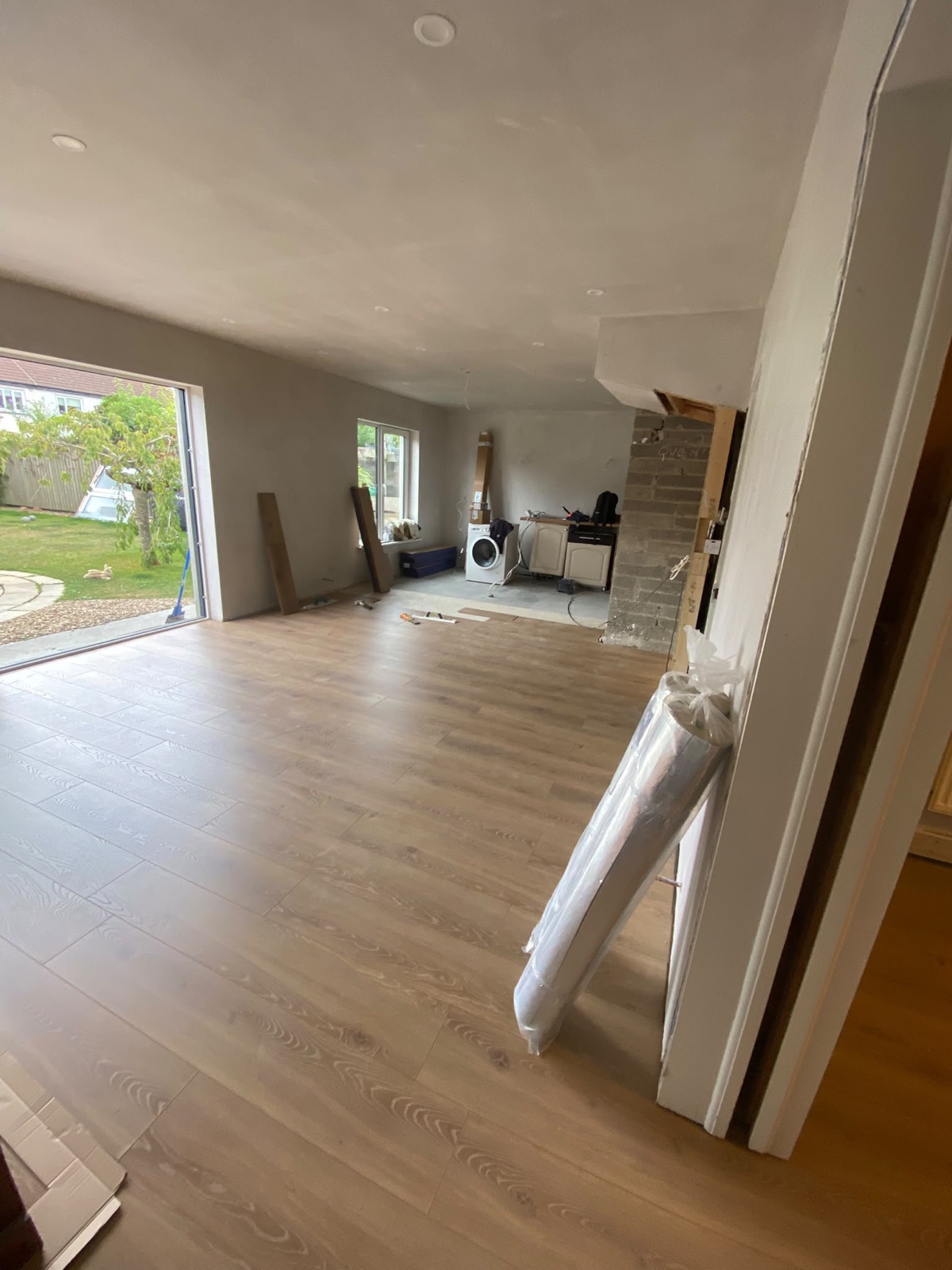 Finished open-plan room with flush plastered ceiling and new flooring after beam installation.