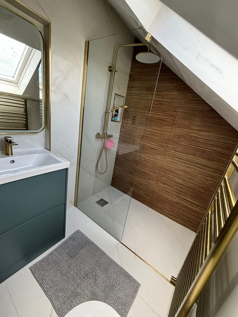 Compact wet room shower in attic ensuite with roof light and brass fittings