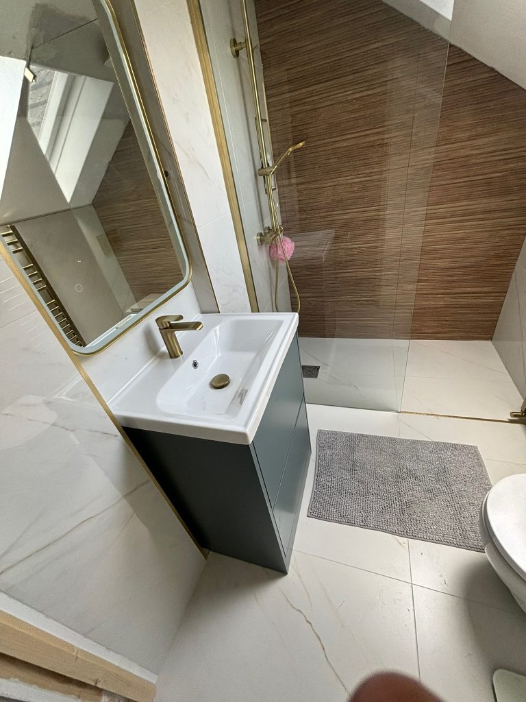 Compact attic ensuite wet room with brass fittings and natural light in Clontarf